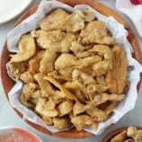 Chicken Skin Chicharon in a white serving bowl with spicy vinegar on the side