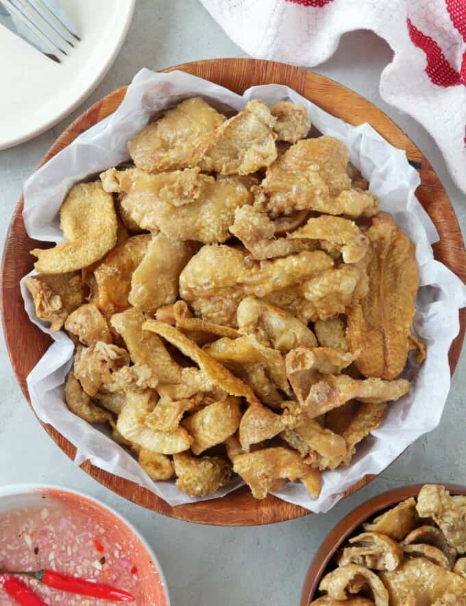 Chicken Skin Chicharon in a white serving bowl with spicy vinegar on the side