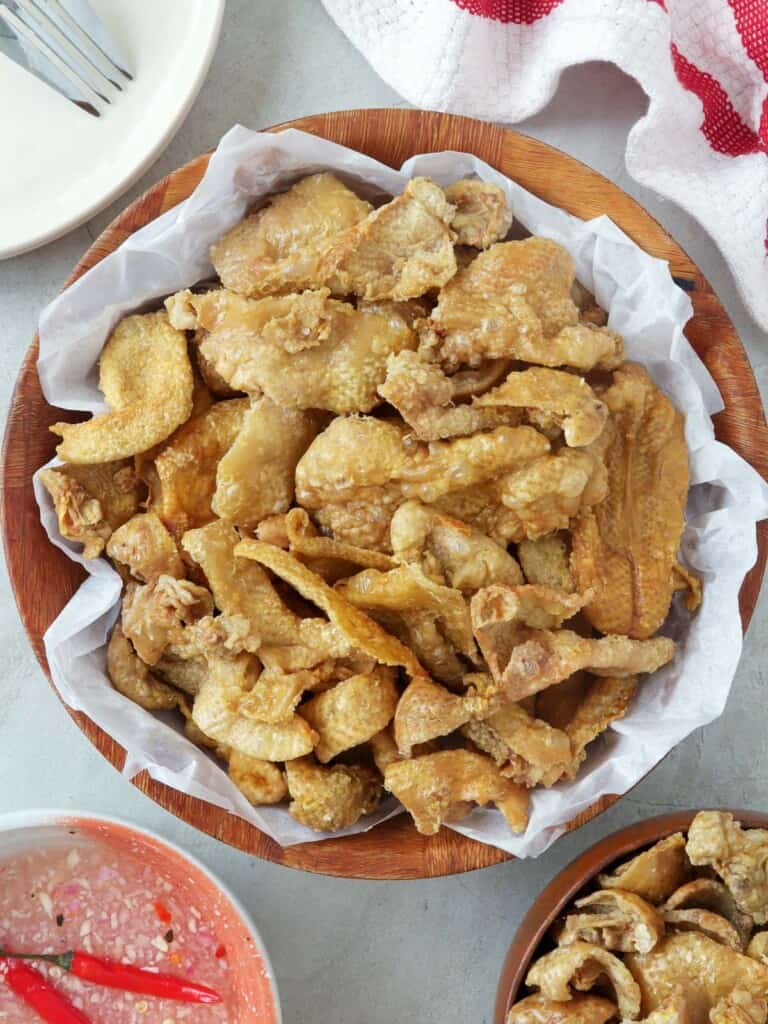 Chicken Skin Chicharon in a white serving bowl with spicy vinegar on the side
