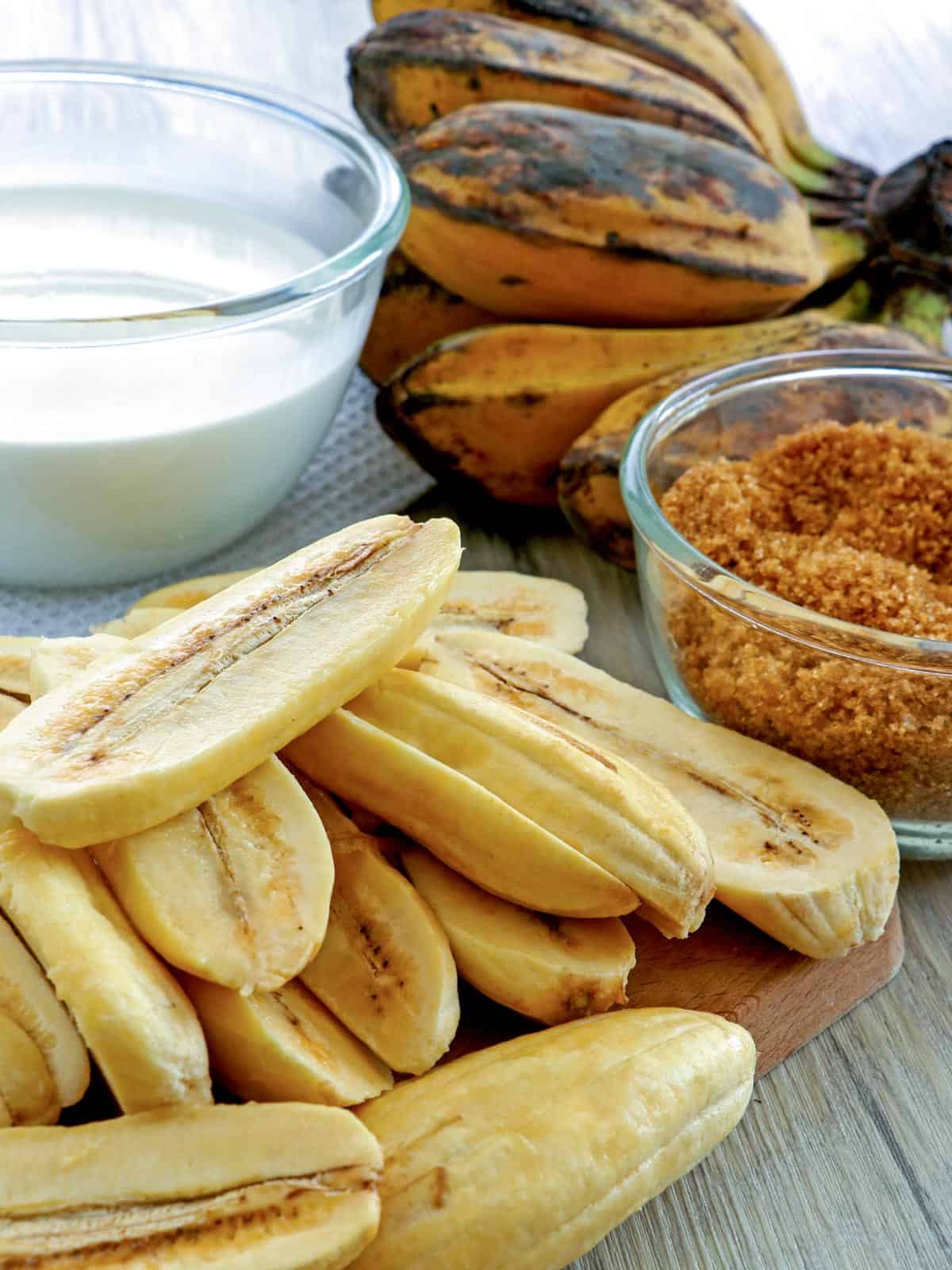 peeled and sliced saba bananas, coconut milk, and brown sugar on the side