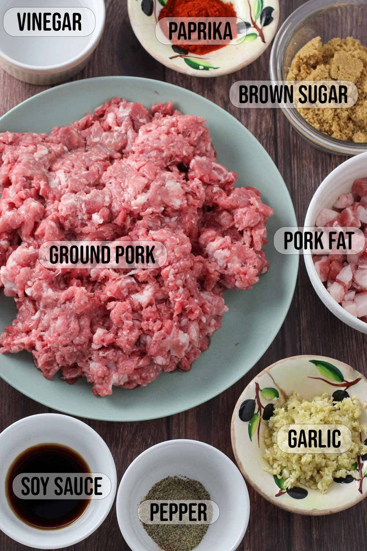 ground pork, ground pork fat, garlic, soy sauce, pepper, paprika, brown sugar, vinegar in bowls.