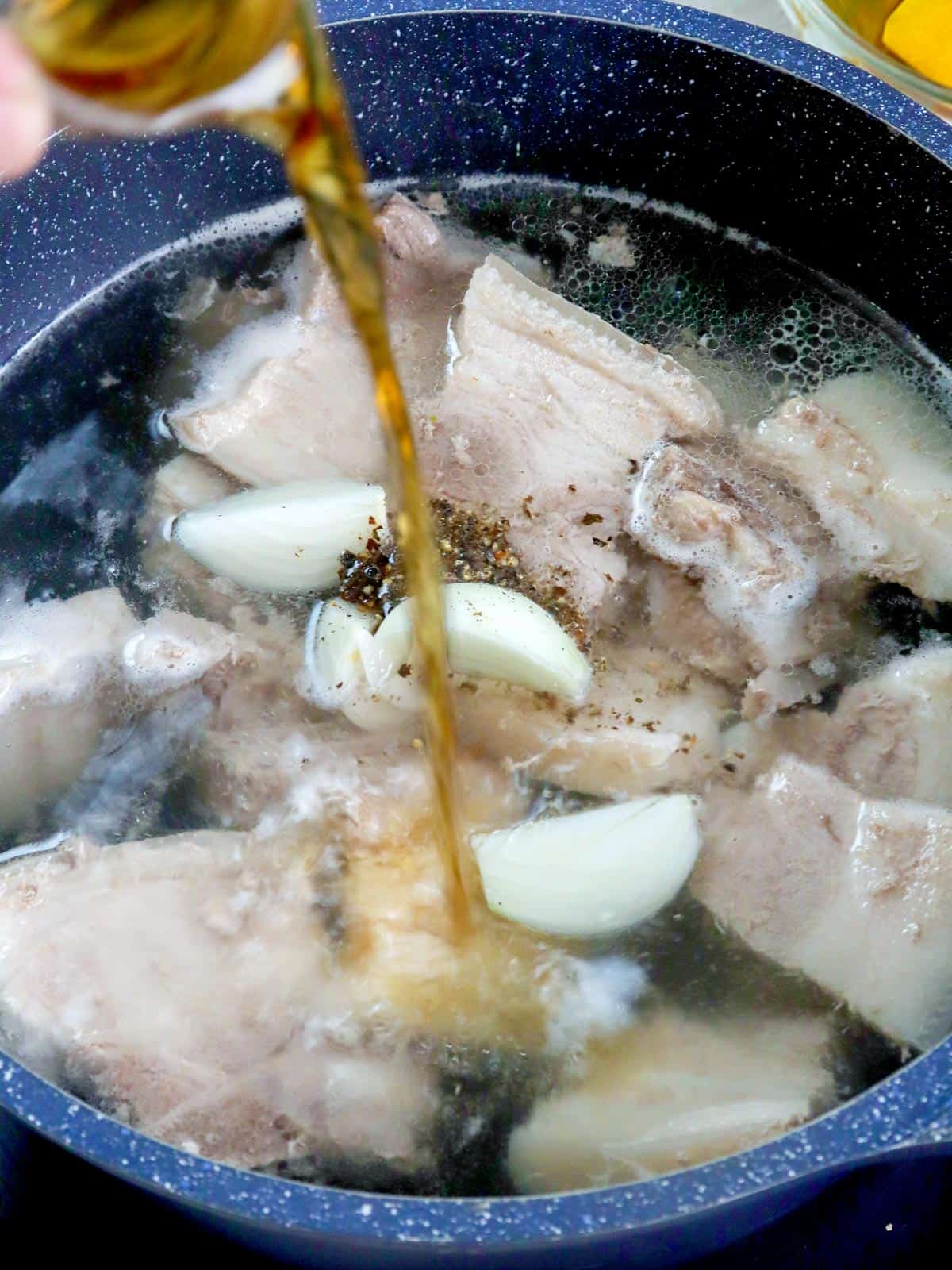 pouring fish sauce in a pot of boiled pork soup