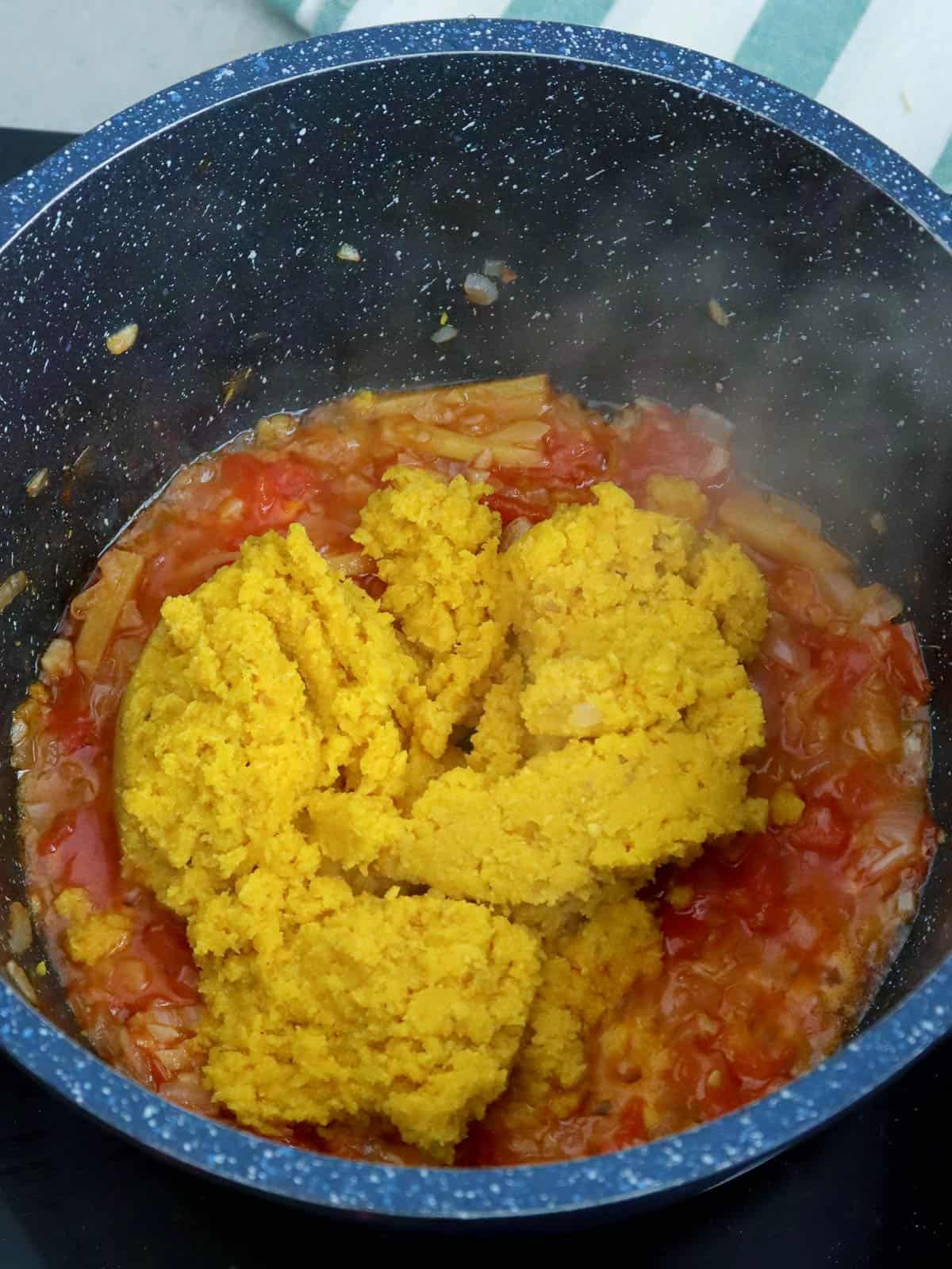 sauteing miso paste in pan with chopped tomatoes and onions