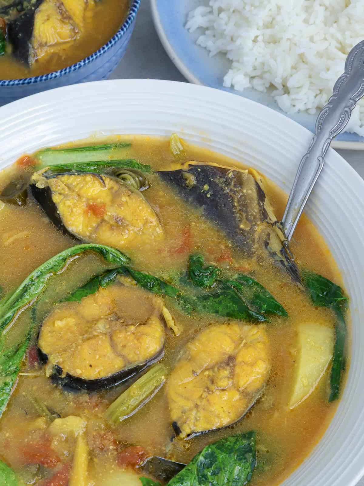 catfish sinigang with miso and mustard leaves in a white serving bowl