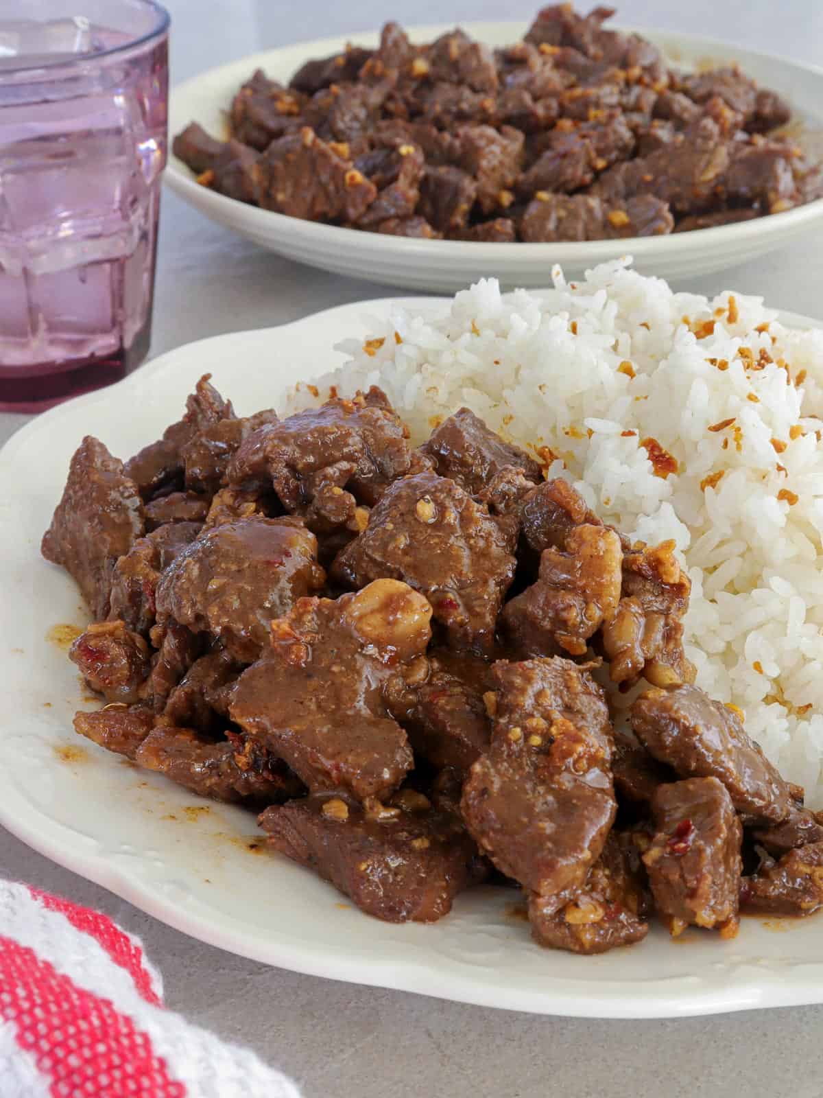 beef salpicao with rice on a white plate.