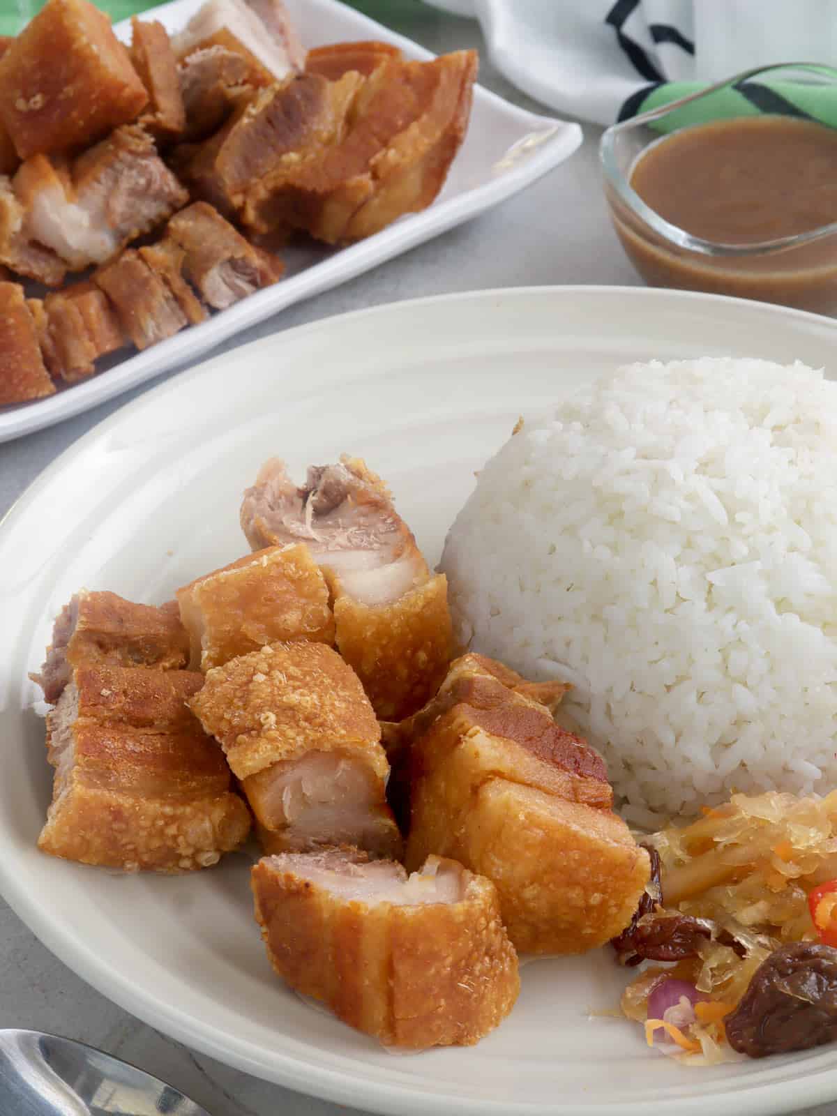 chopped lechon kawali with steamed rice on a white plate