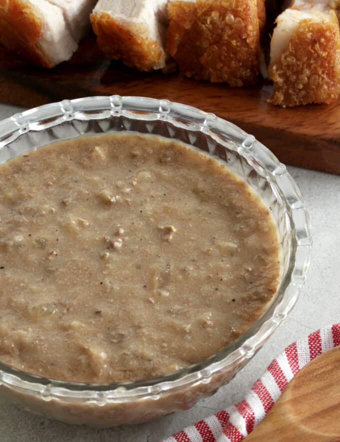 Lechon Sauce in a clear bowl with lechon kawali on the side