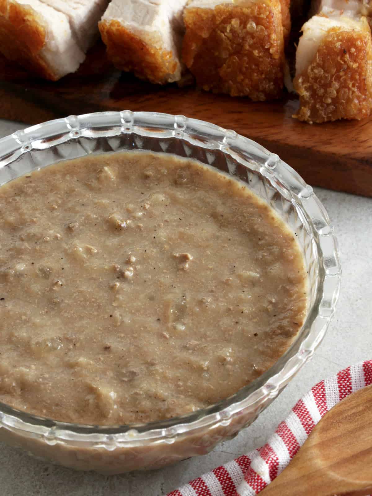 Lechon Sauce in a clear bowl with lechon kawali on the side