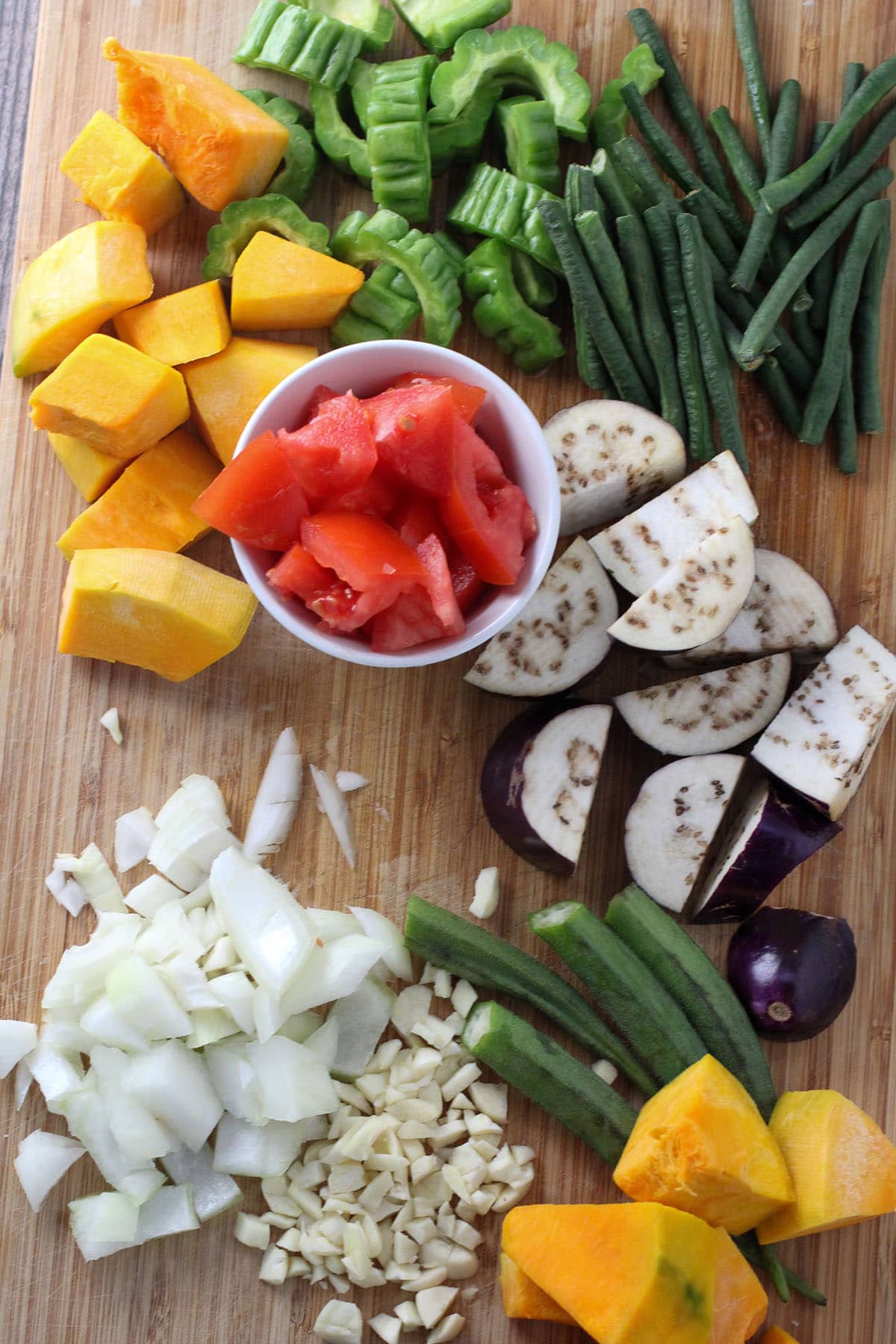 kalabasa, sitaw, okra, eggplant, tomatoes, onions, garlic on a cutting board