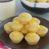 Cheese Puto on a brown serving plate with cup of coffee in the background.