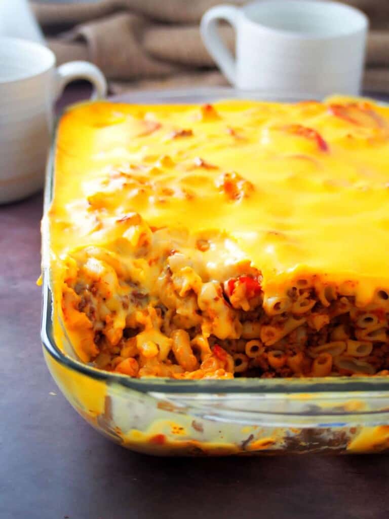 baked mac topped with cheese sauce in a glass baking dish