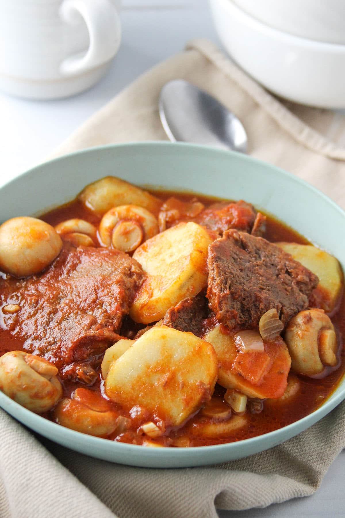 ox tongue stew with mushrooms and potatoes in a blue serving bowl