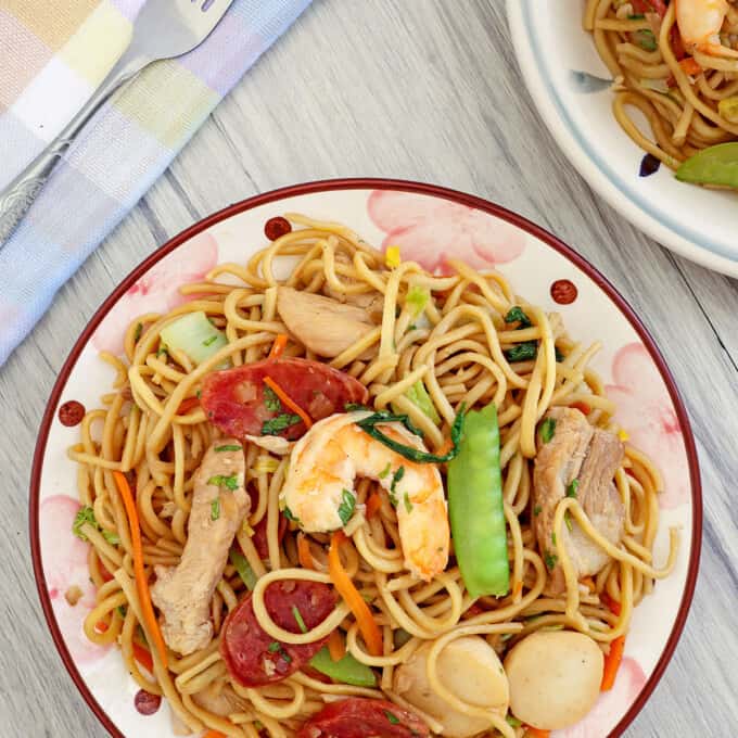 Filipino pancit canton guisado with shrimp, sausage, and veggies on a plate