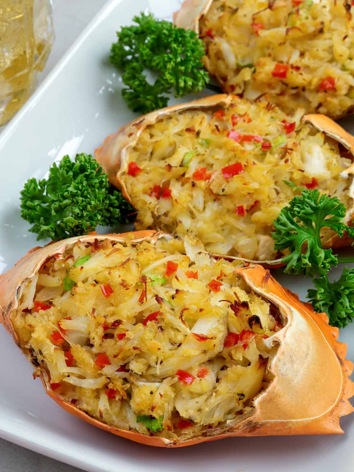 Filipino-style stuffed crab shells on a white serving platter.