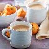 Tsokolate in white cups with a bowl of muffins on the side