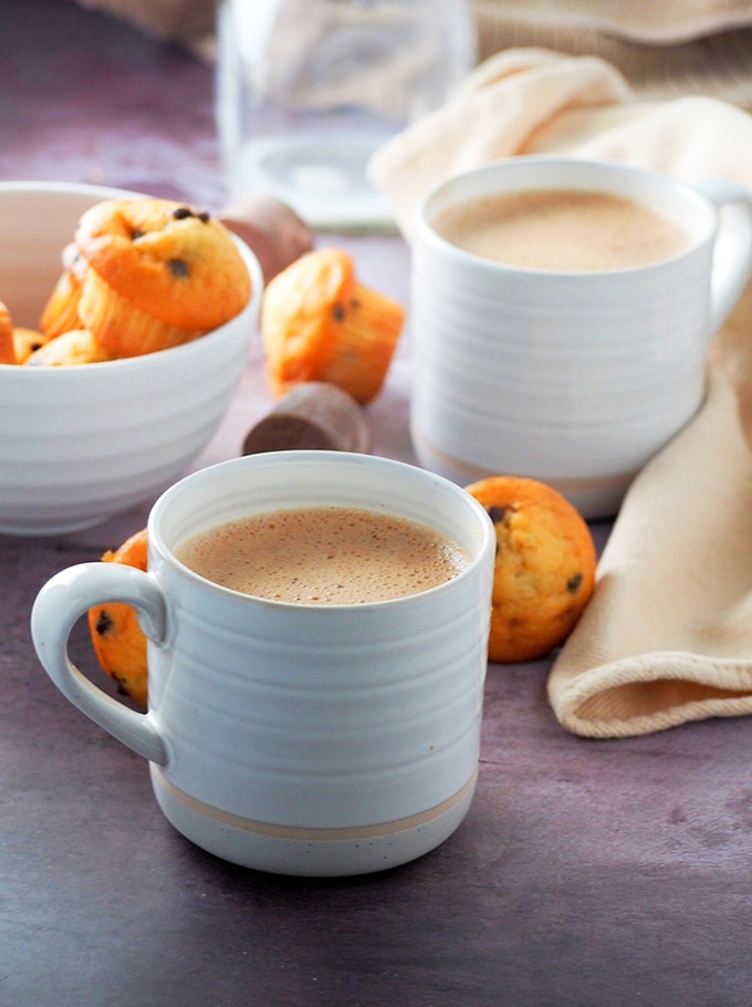 Tsokolate in white cups with a bowl of muffins on the side