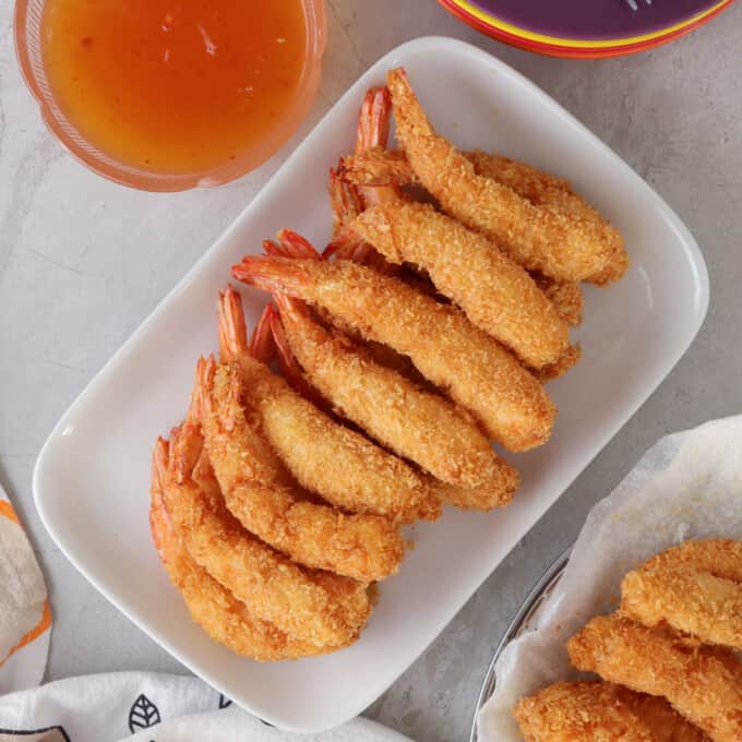 Coconut Shrimp on a serving platter with a small bowl of sweet chili sauce on the side