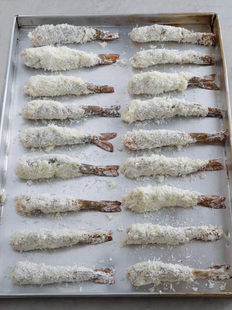 coconut shrimp in a single layer on a baking sheet
