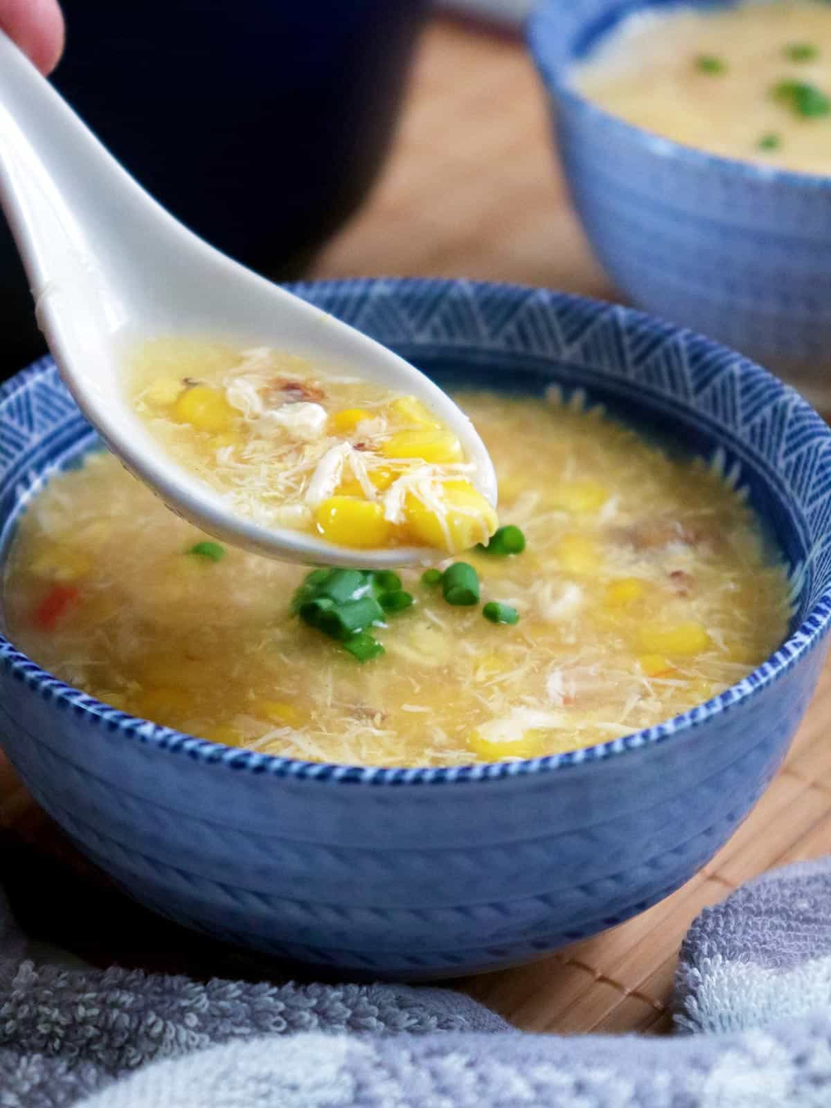 eating creamy crab soup with a Chinese soup spoon from a blue bowl