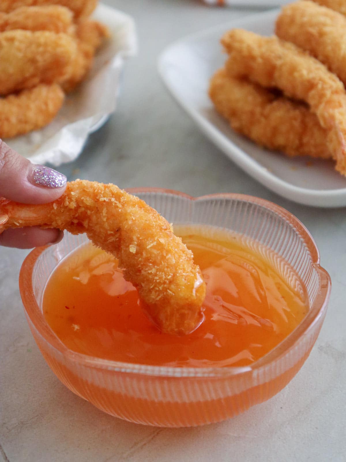 dipping crispy coconut shrimp in sweet chili sauce