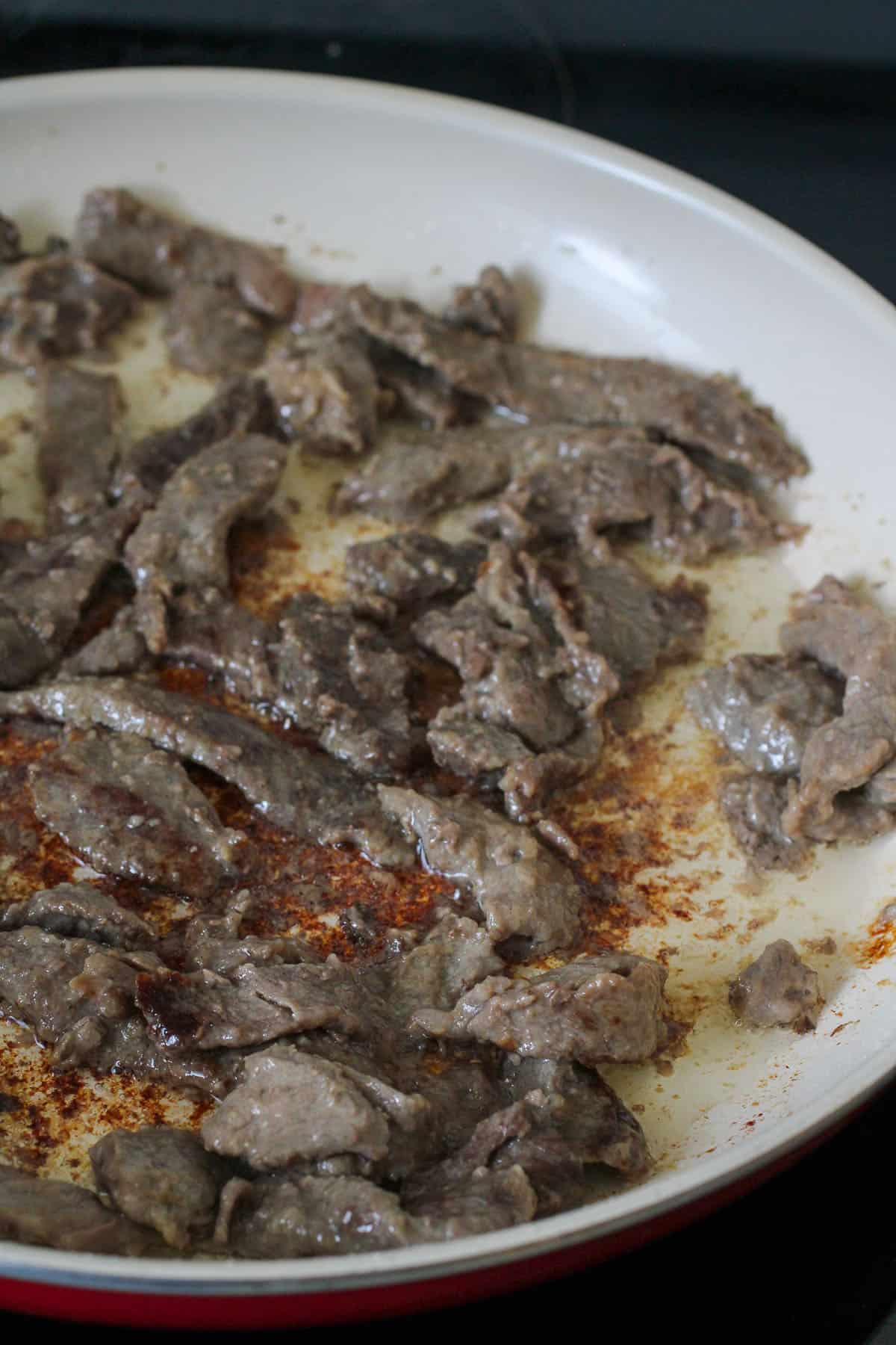 stir-frying sirloin slices in a pan