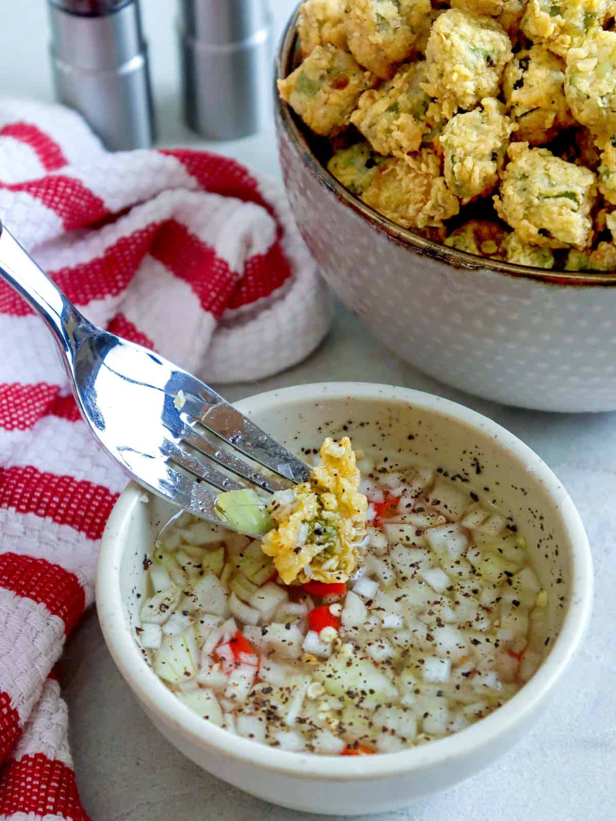 dipping fried okra in spiced vinegar with a fork