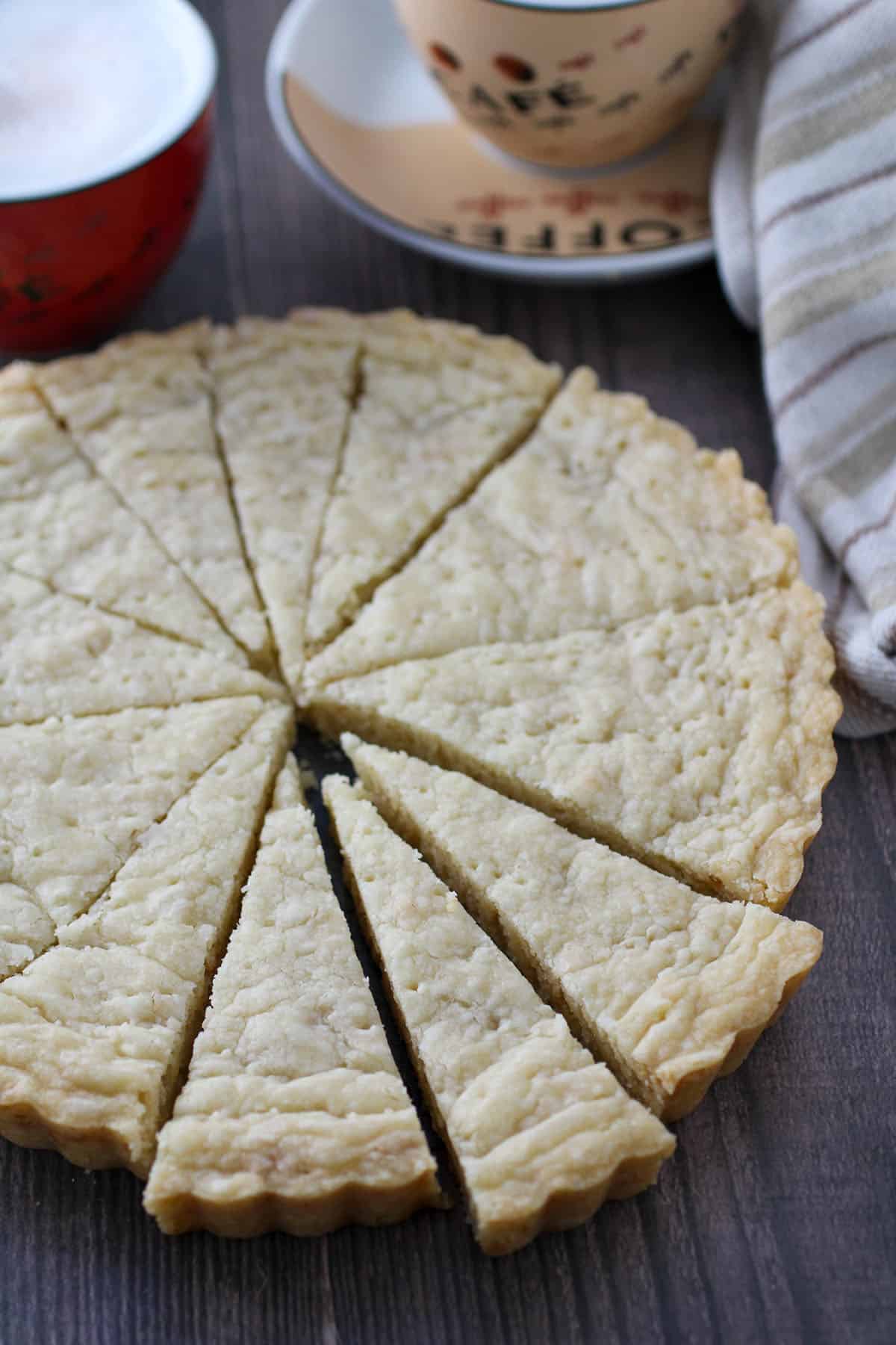 round Pinipig Shortbread Cookies cut into serving slices with a cup of coffee in the background.