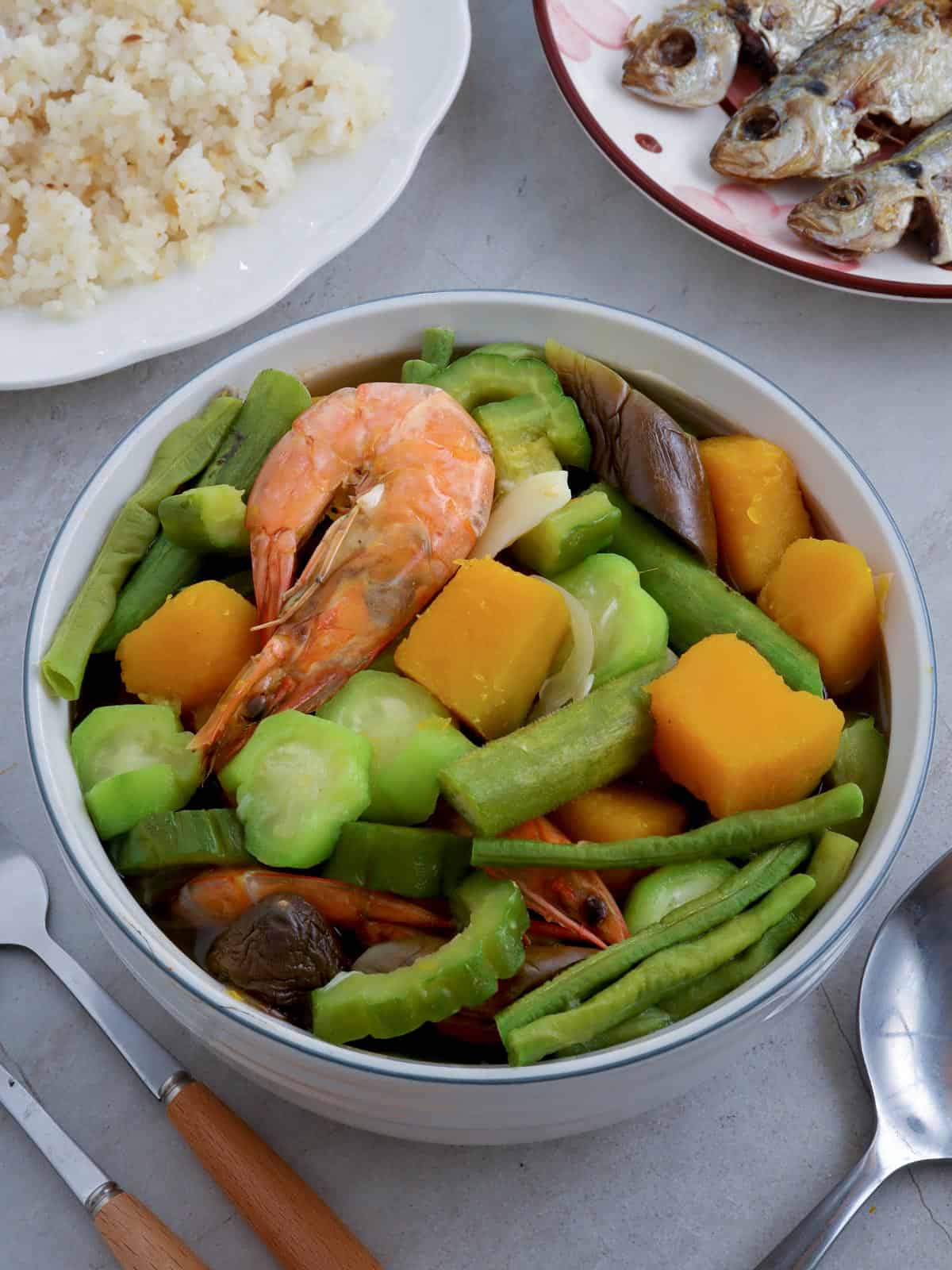 laswa in a white bowl with steamed rice and fried fish on the side