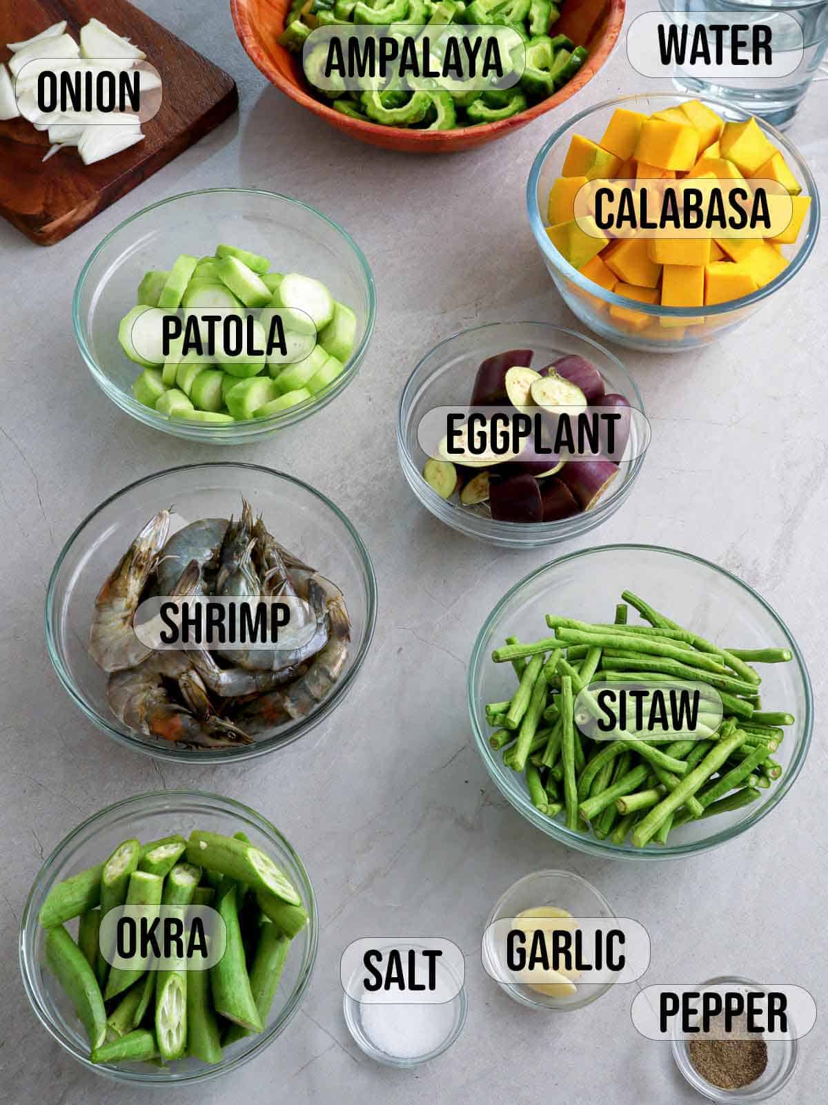 eggplant, calabasa, shrimp, sitaw, okra, patola, ampalaya, onion, garlic, and salt in bowls.