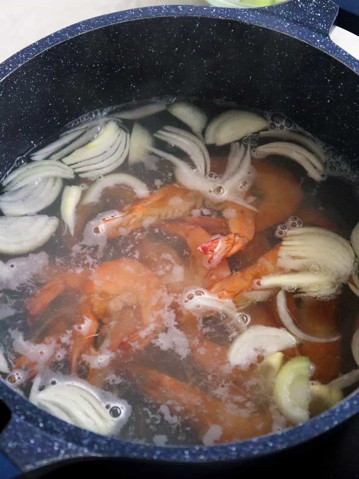 cooking shrimp in a pot of water, onions, and garlic