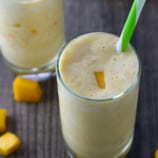 drinking mango smoothie with straw from a glass