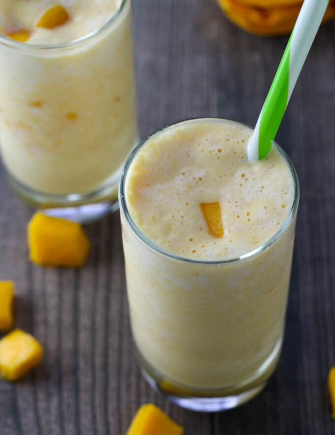 drinking mango smoothie with straw from a glass