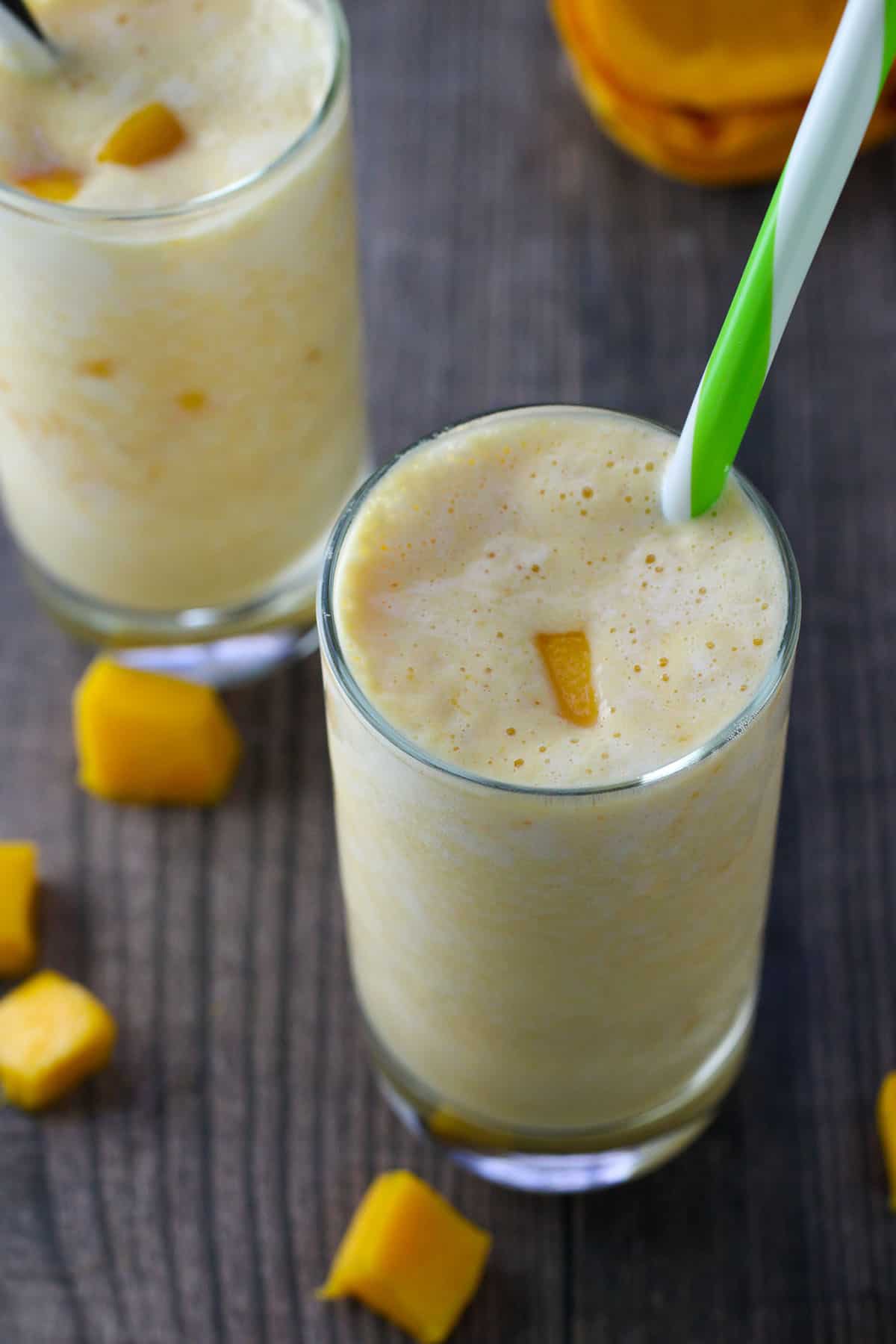 drinking mango smoothie with straw from a glass