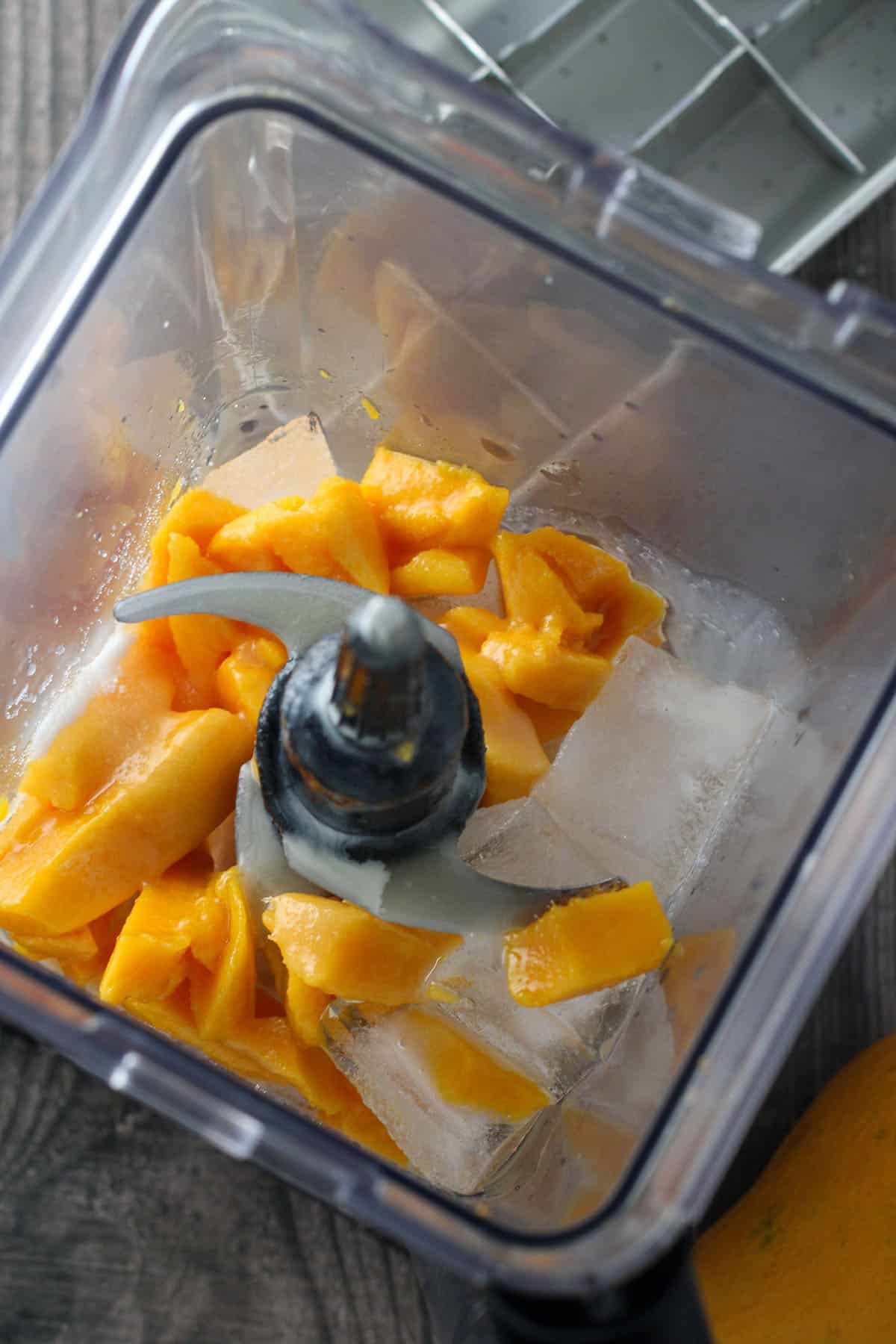 blending mangoes, milk, ice in a blender