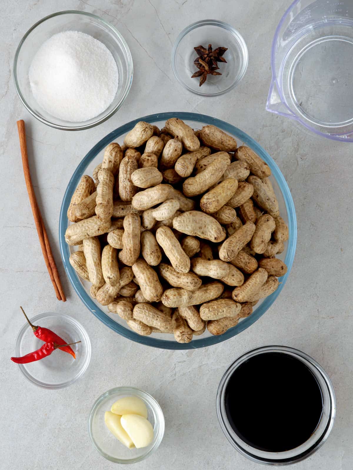 raw shell-on peanuts, soy sauce, sugar, chili peppers, garlic cloves, soy sauce, peppercorns, star anise in individual bowls