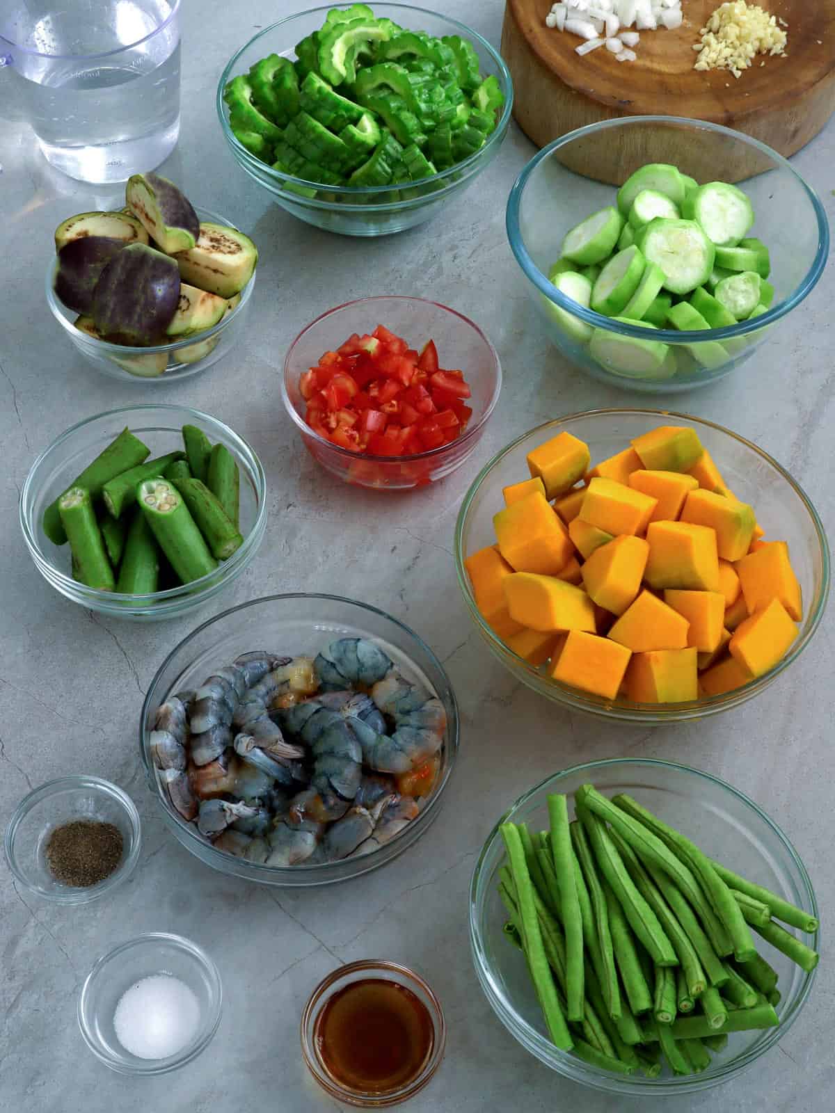 sitaw, shrimp, kalabasa, patola, amapalaya, eggplant, tomatoes, okra, onions, fish sauce in bowls