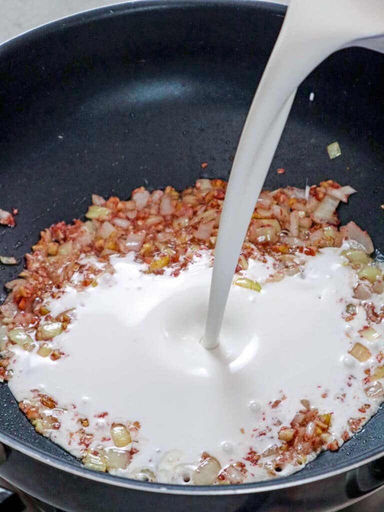 pouring coconut milk to sauteed onions, garlic, and sauteed shirmp paste