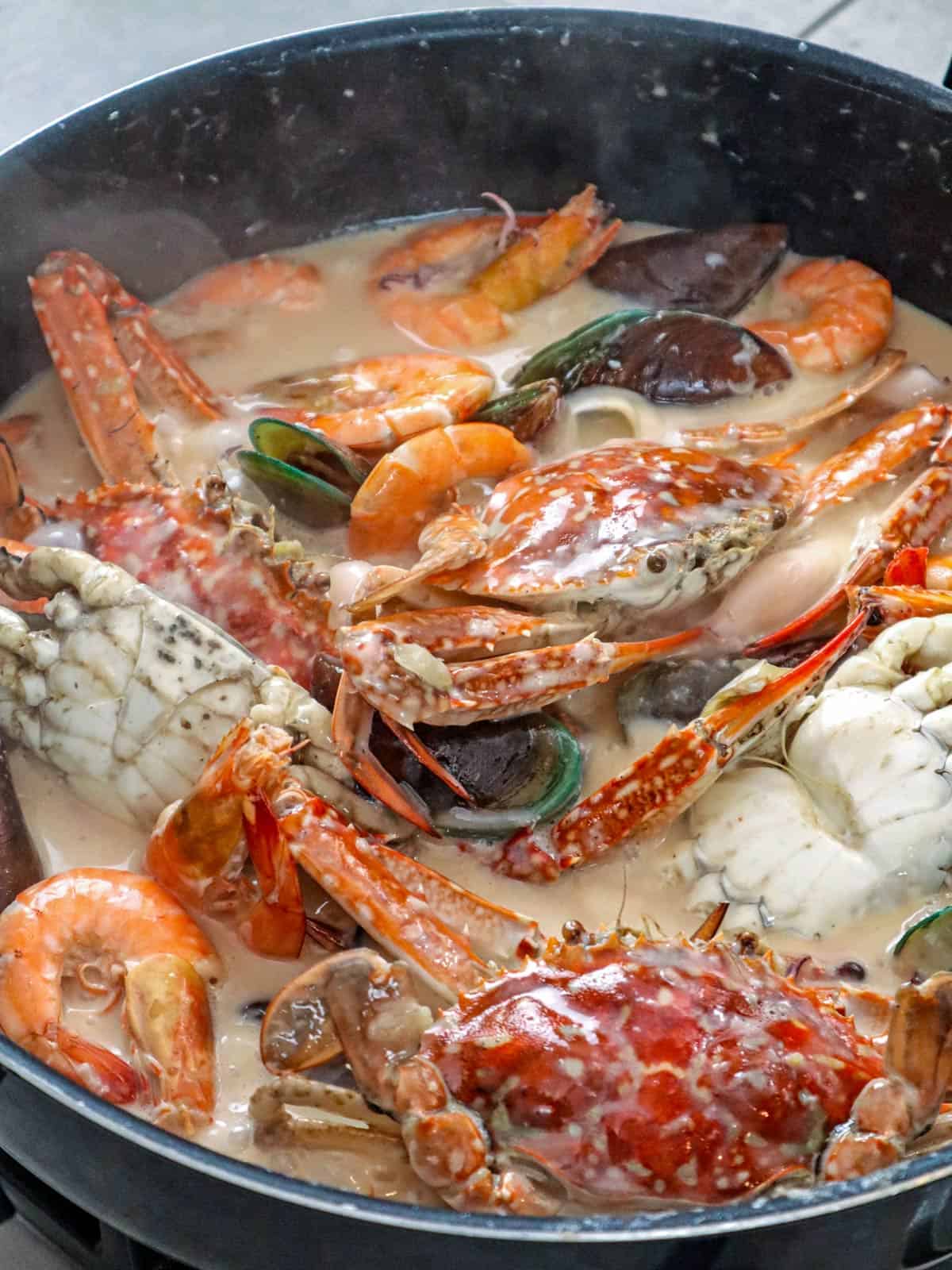 shrimp, crab, mussels, and squid simmering in coconut sauce
