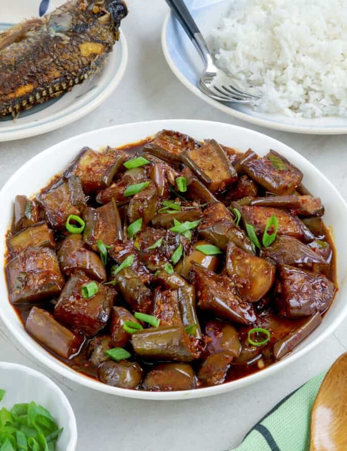 talong stir-fry in a white bowl with steamed rice and fried fish on the side