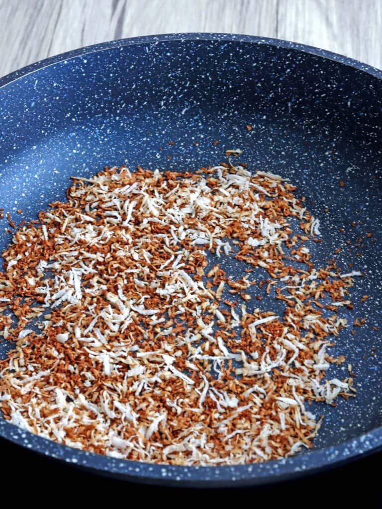 toasting shredded coconut flakes in a pan