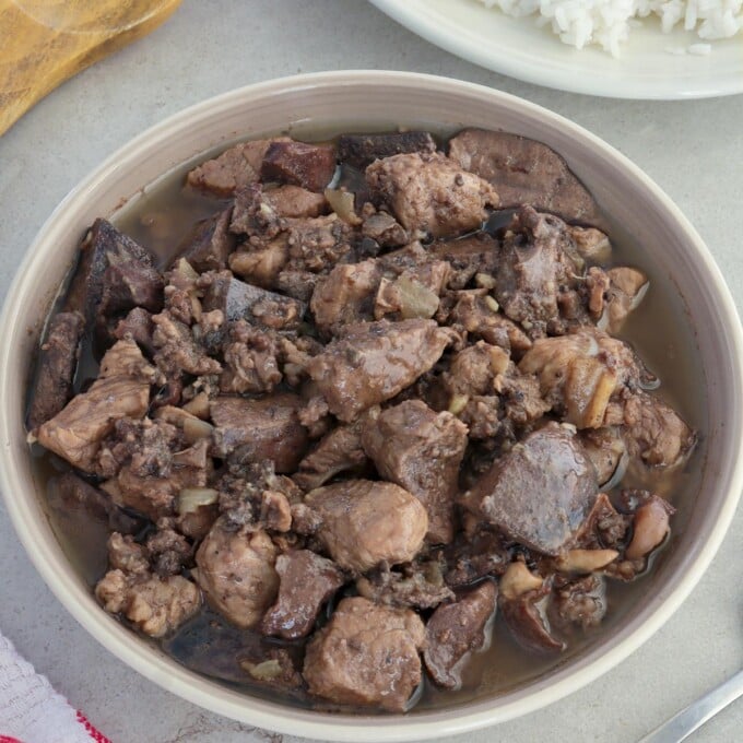 Kilayin in a white serving bowl with a plate of steamed rice on the side