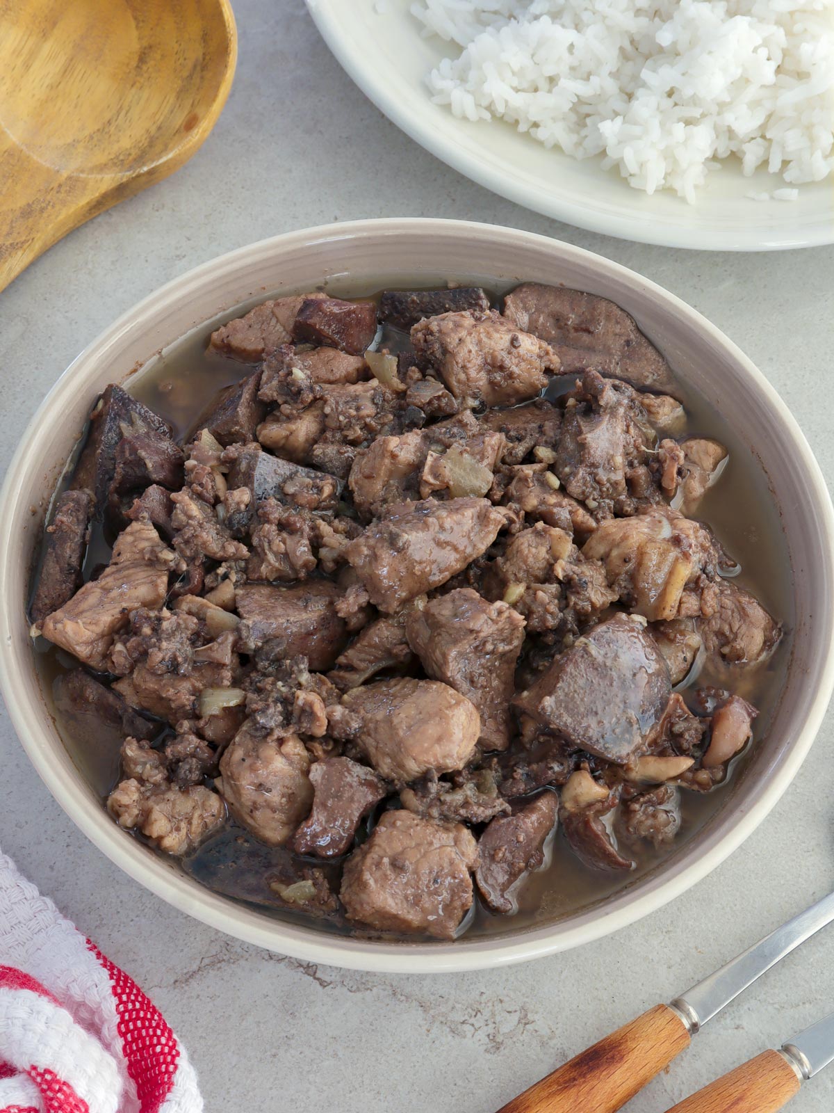 Kilayin in a white serving bowl with a plate of steamed rice on the side