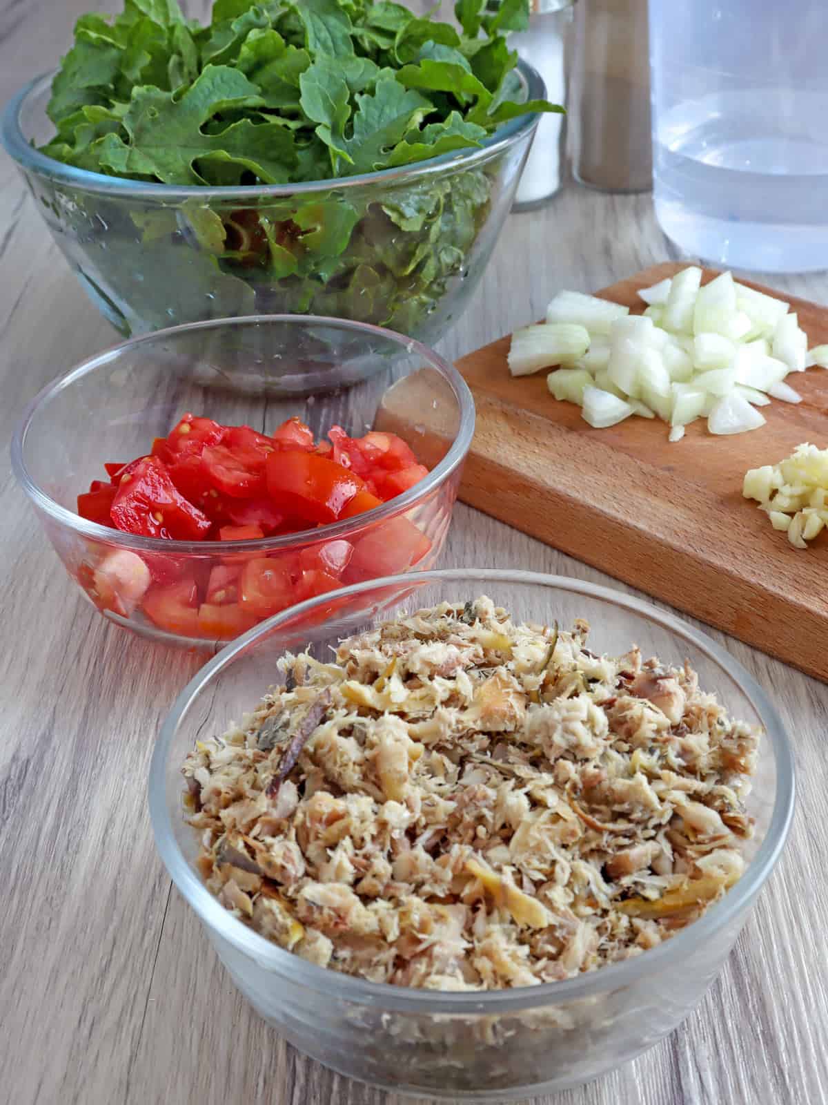 fresh ampalaya leaves, flaked tinapa, chopped tomatoes, chopped onions, minced garlic, water