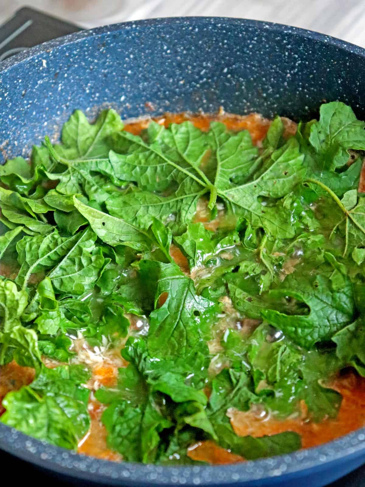 cooking ampalaya leaves with smoked fish in a pot