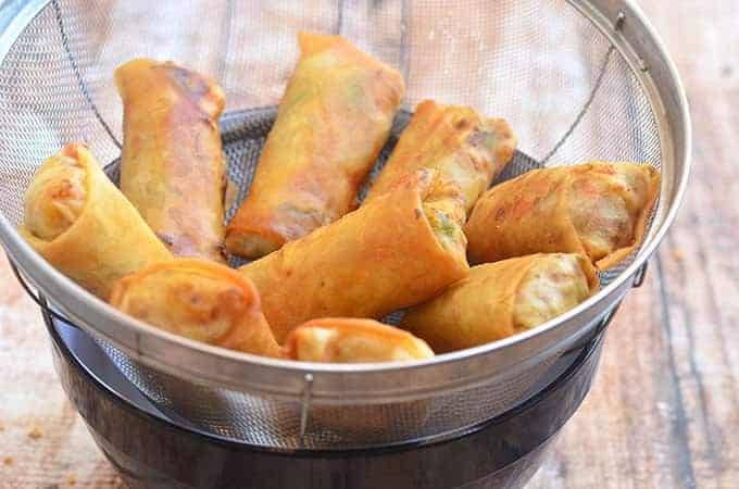 Fried lumpia draining in a metal colander