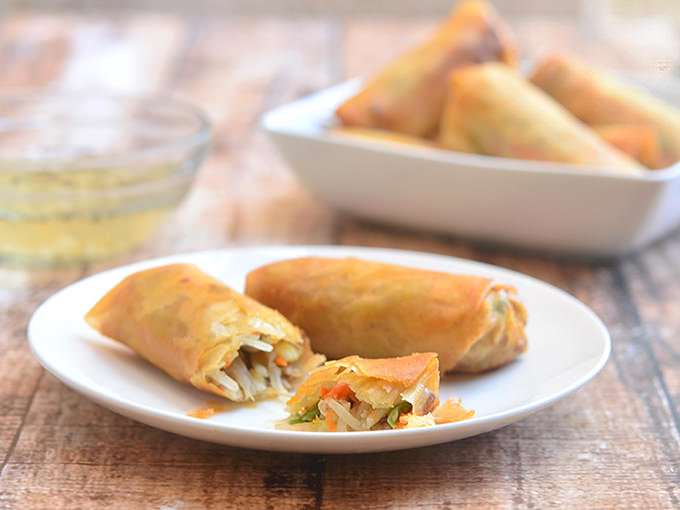 Lumpiang Prito with Pork om a white serving plate with a bowl of spicy vinegar on the side