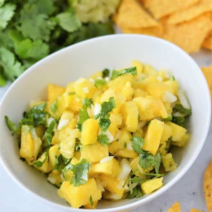 Pineapple Salsa in a white bowl with chips on the side