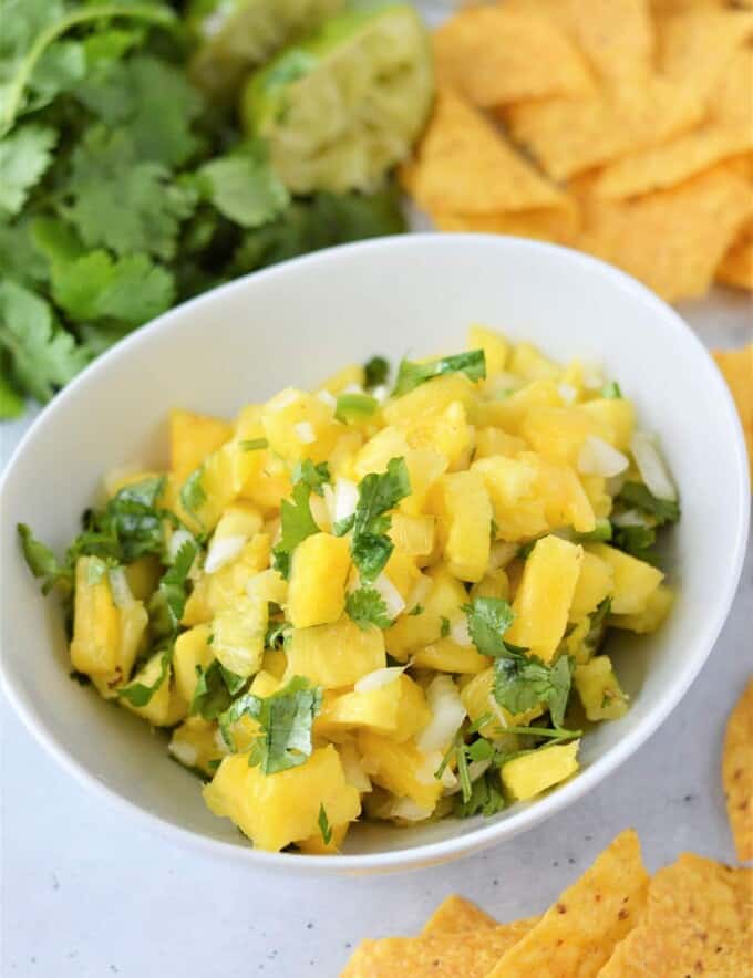 Pineapple Salsa in a white bowl with chips on the side