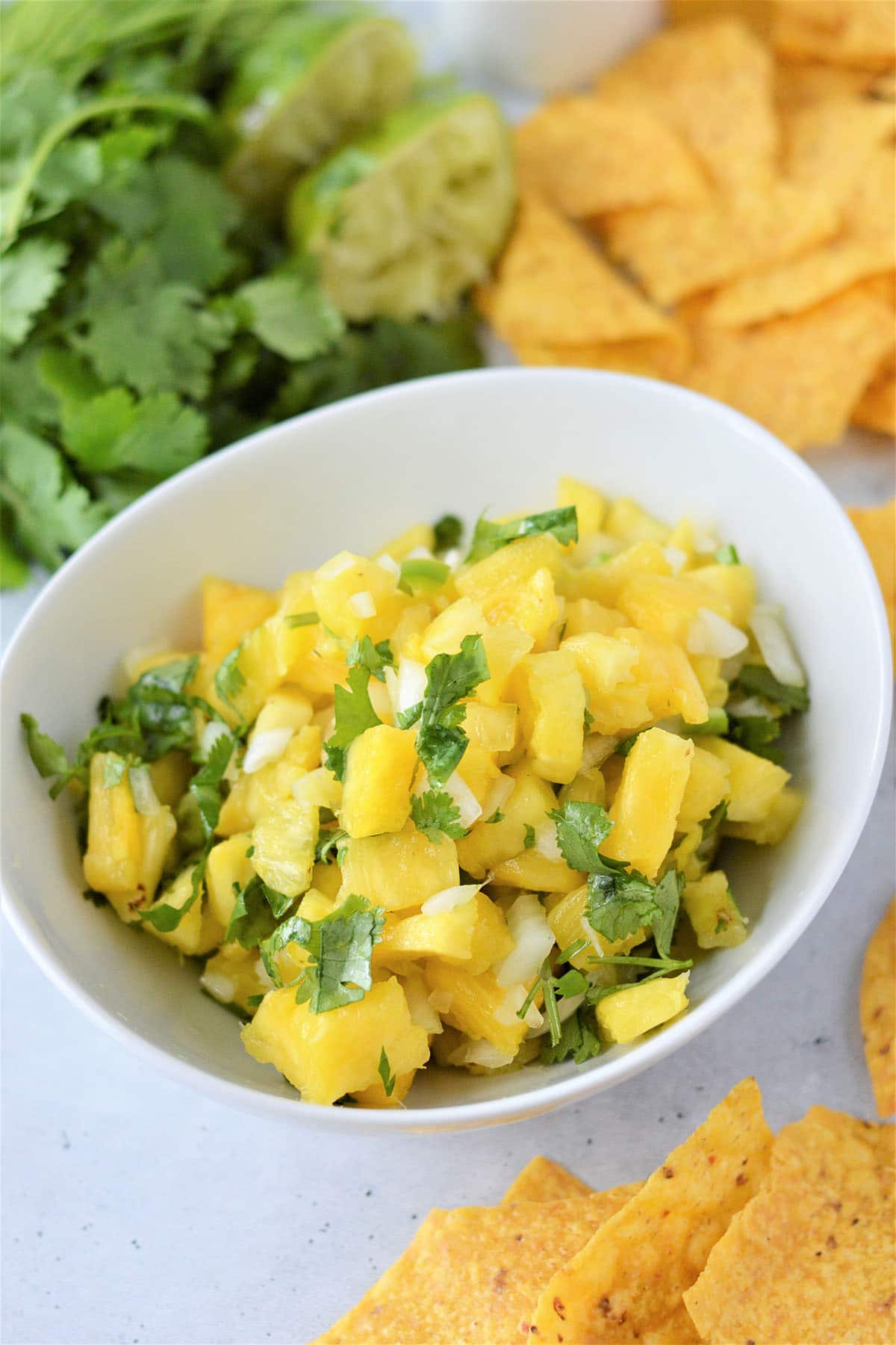 Pineapple Salsa in a white bowl with chips on the side