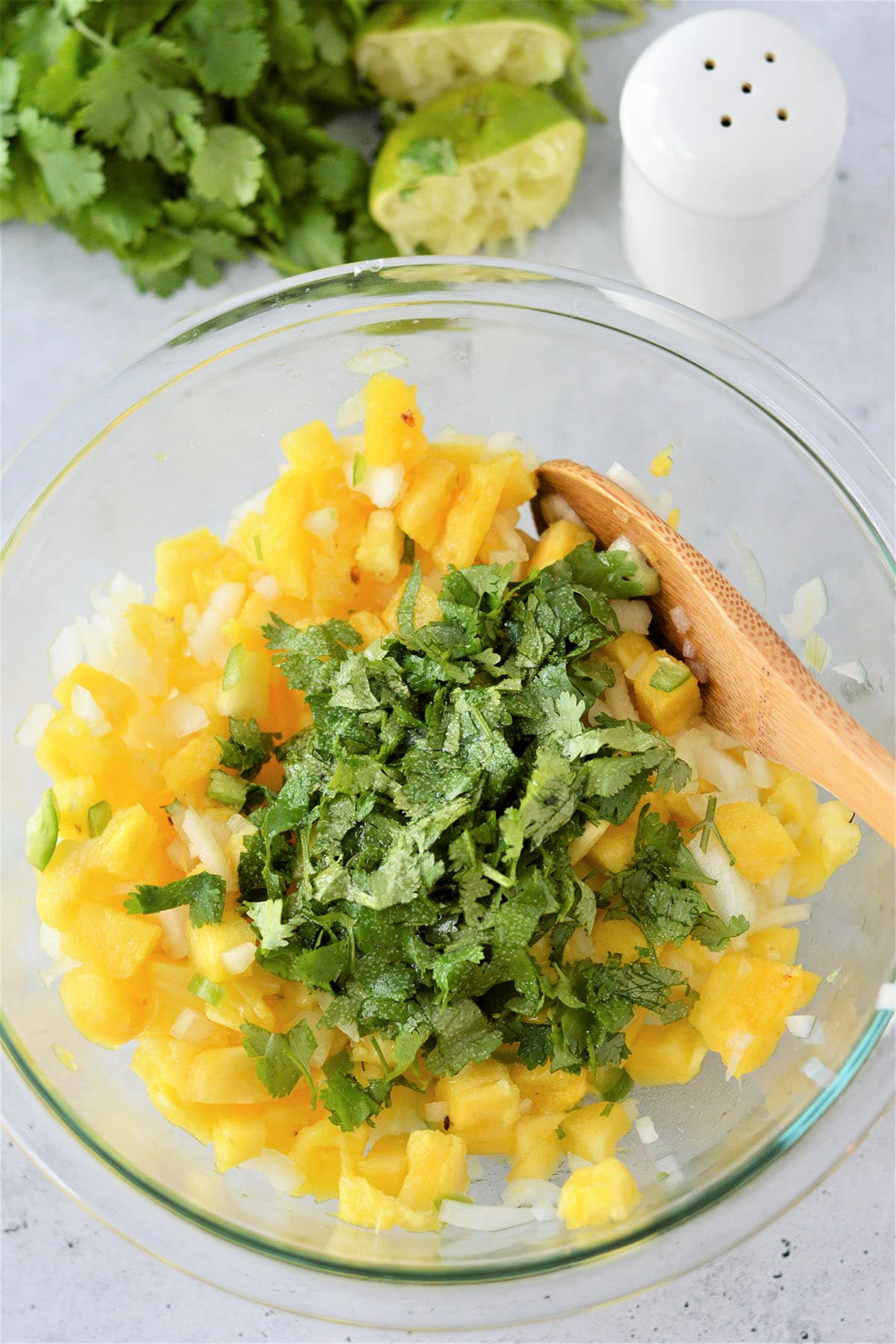 mixing diced pineapples, chopped onions, and chopped cilantro